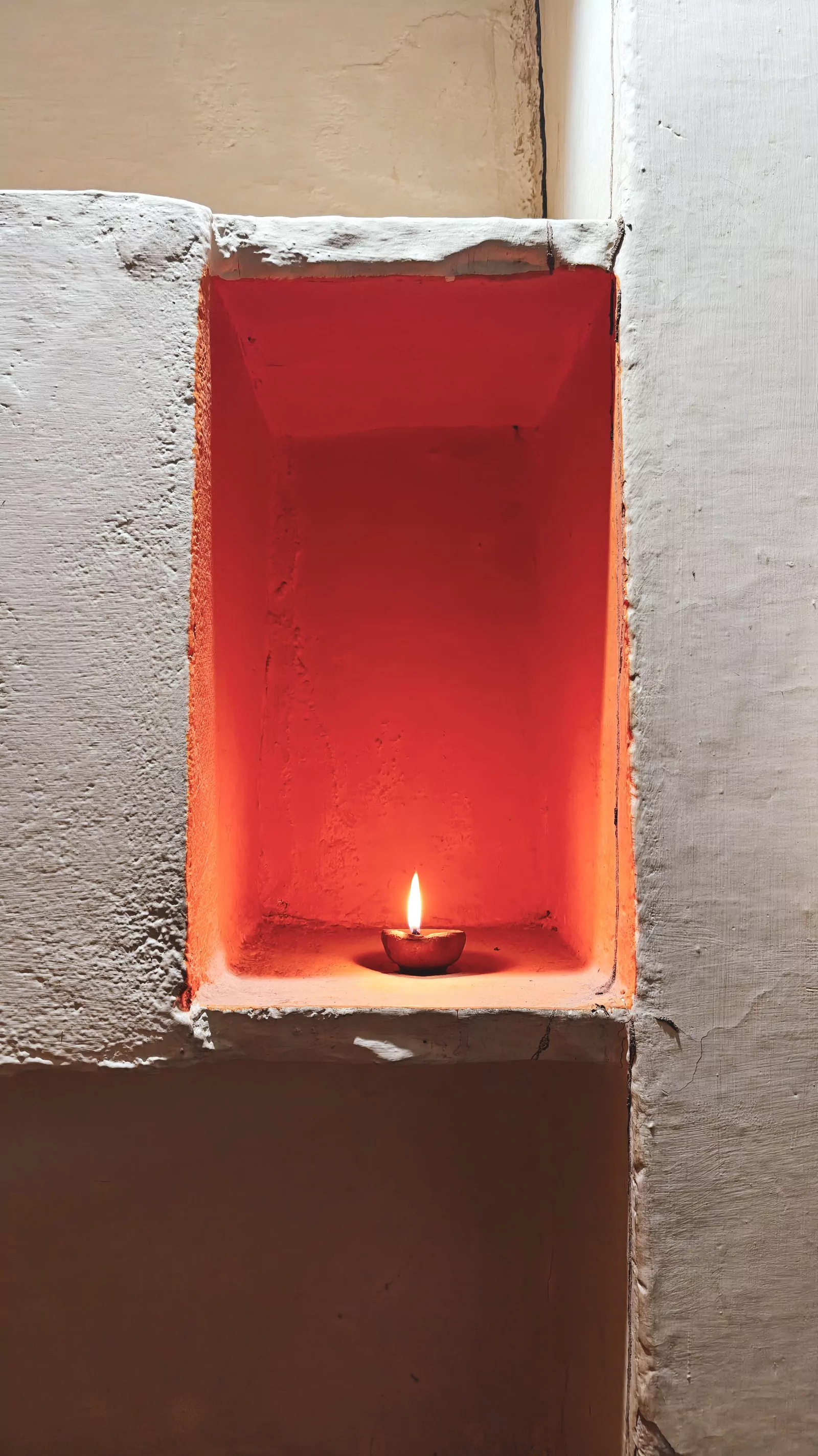 Alcôve rouge éclairée par une lampe en terre cuite
