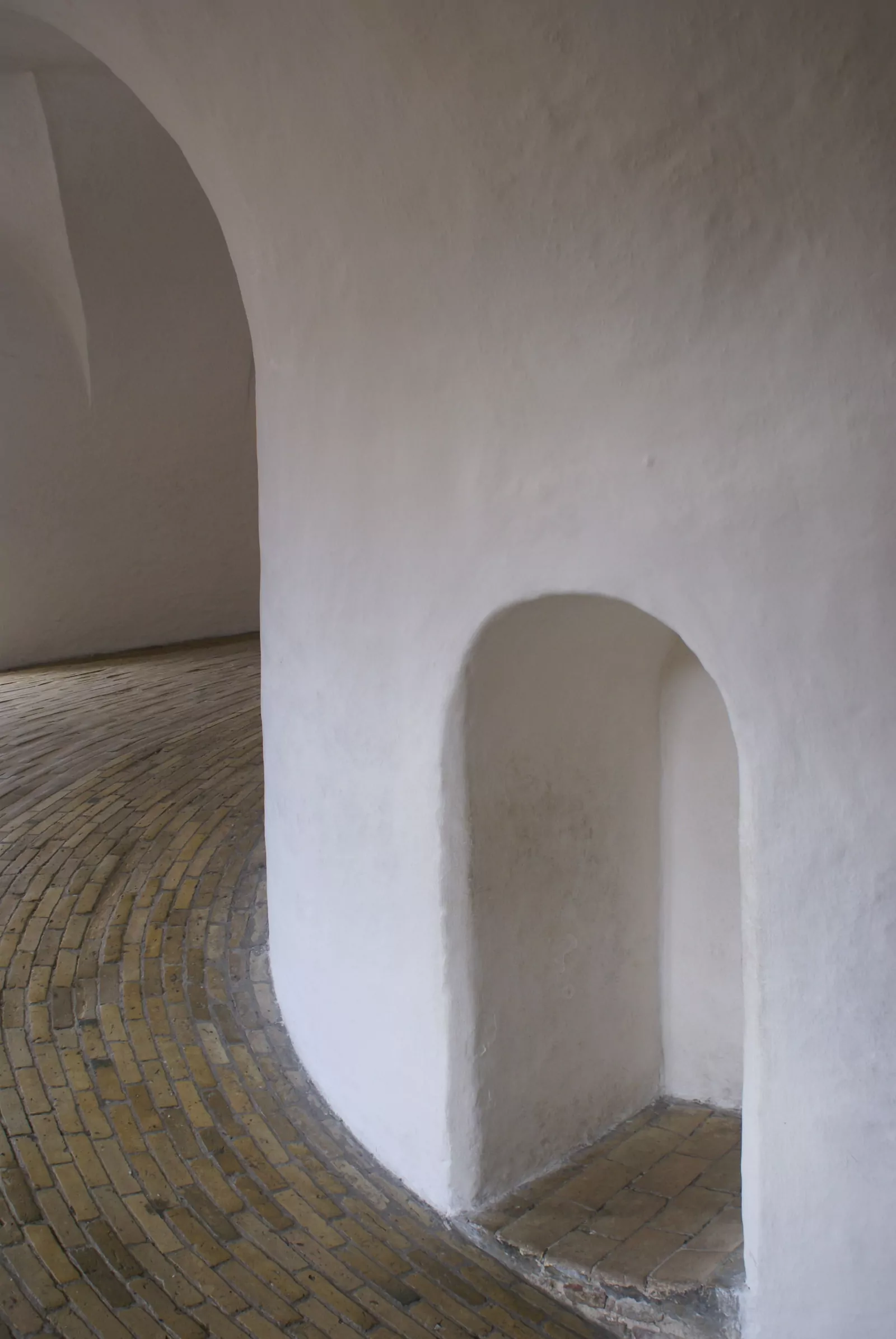 Murs blancs incurvés avec une niche en arc et un sol de briques